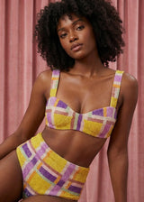 Woman wearing a colorful plaid bikini against a pink background