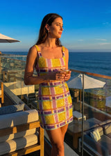 Woman in a colorful dress standing on a balcony with ocean view