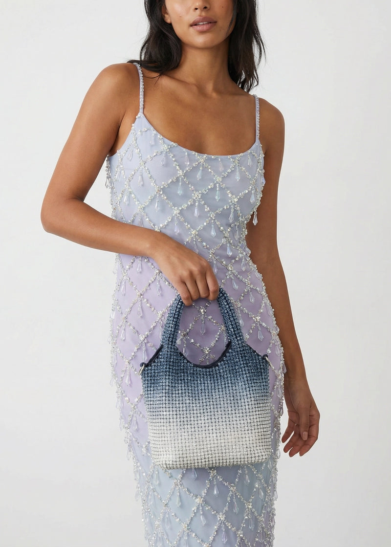 Woman holding a beaded handbag against a plain background