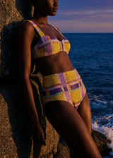 Person wearing a colorful checkered bikini by the ocean