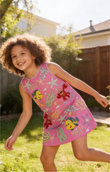 Child wearing a pink dress with cartoon characters outdoors