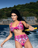 Woman in a pink bikini holding a paddle with a scenic background