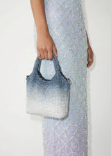 Person holding a patterned handbag with a light blue dress.