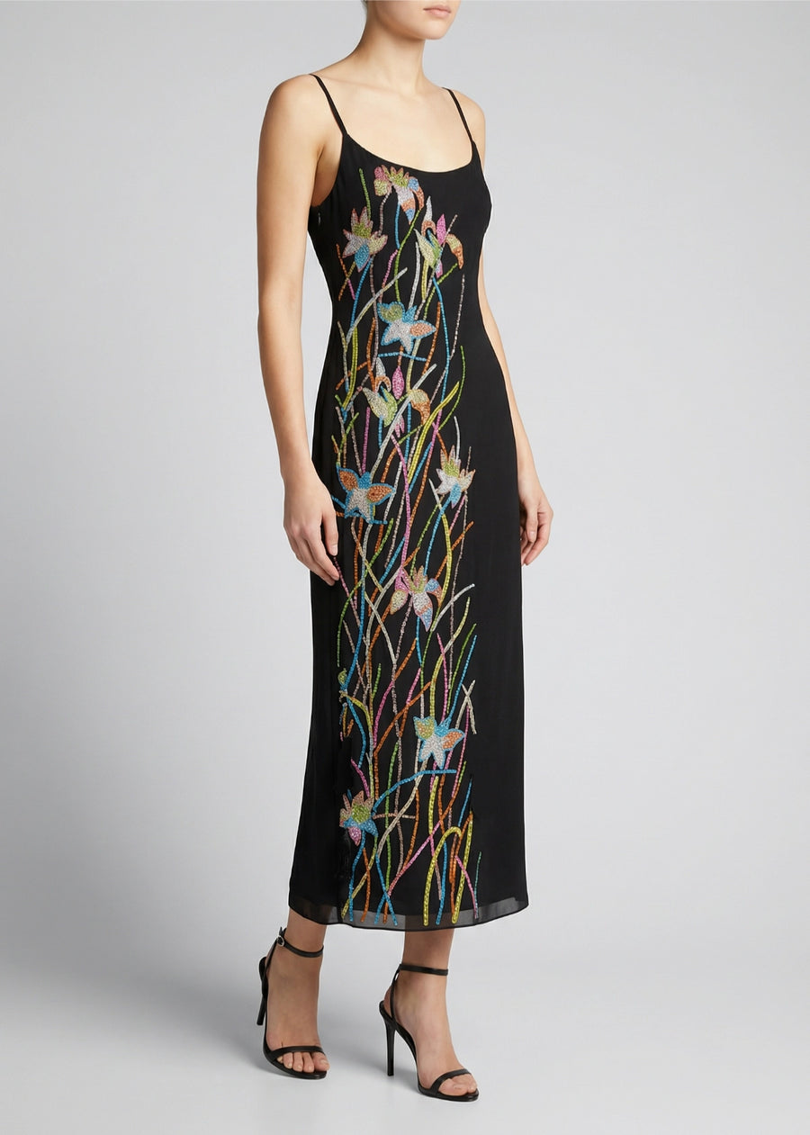 Black slip dress with colorful floral embroidery on a plain background