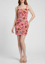 Woman wearing a pink dress with colorful sea-themed pattern on a white background