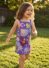 Child wearing a colorful dress with sea-themed designs outdoors on grass