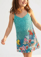 Child wearing a sequined dress with ocean-themed design on a white background