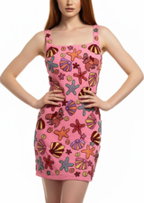 Model wearing a pink dress with colorful shell pattern on a white background
