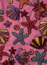Colorful sea-themed fabric with starfish, shells, and fish on a pink background