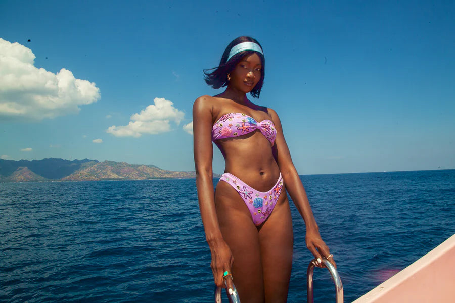 A black women in Quinn Clasp Closure Bikini Top in Lilac in Yacht 